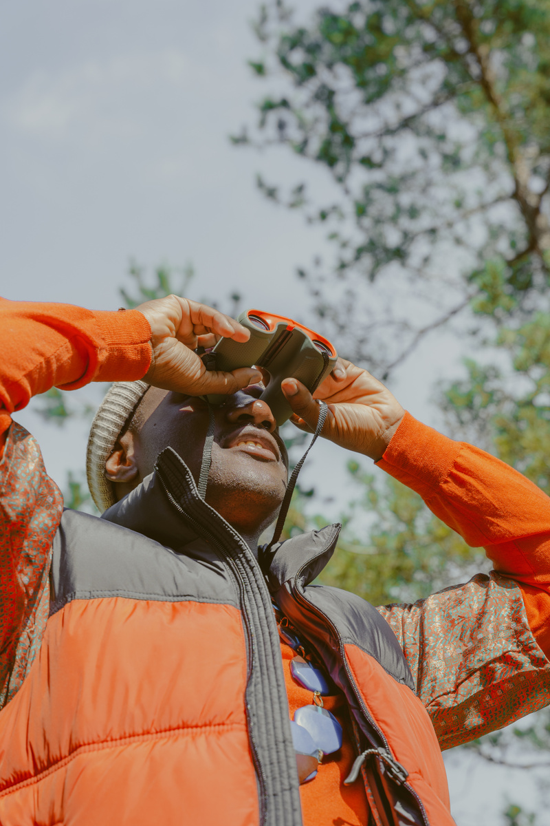 a person in an orange vest is looking through binoculars