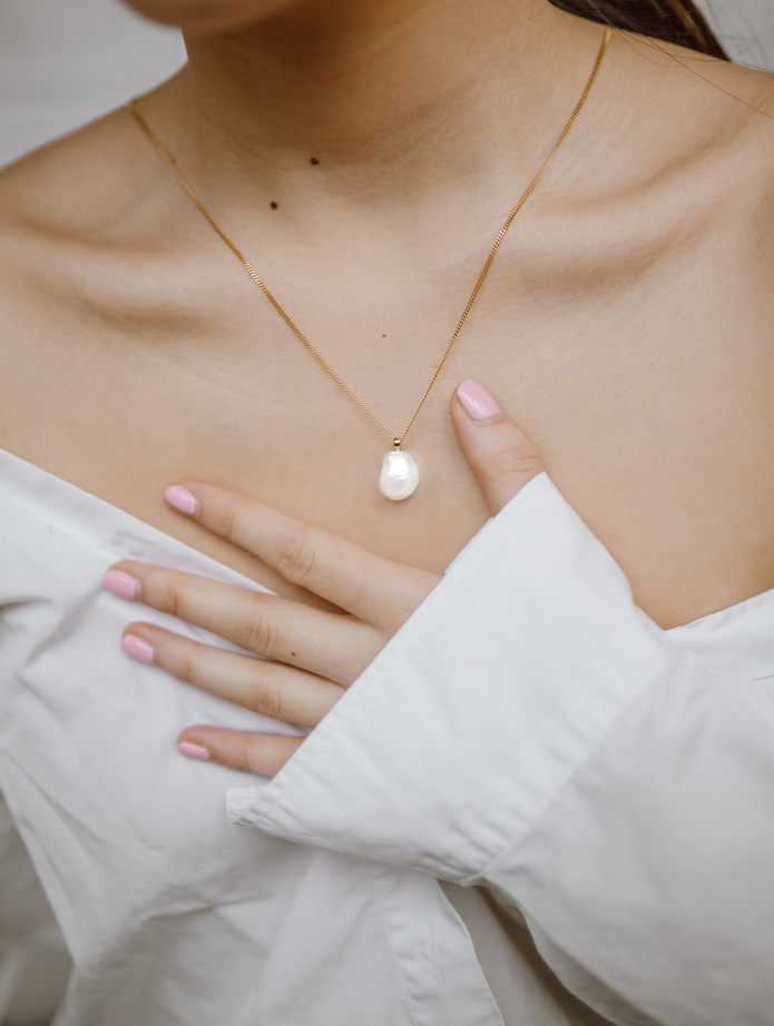 a person wearing a white shirt with a pearl necklace